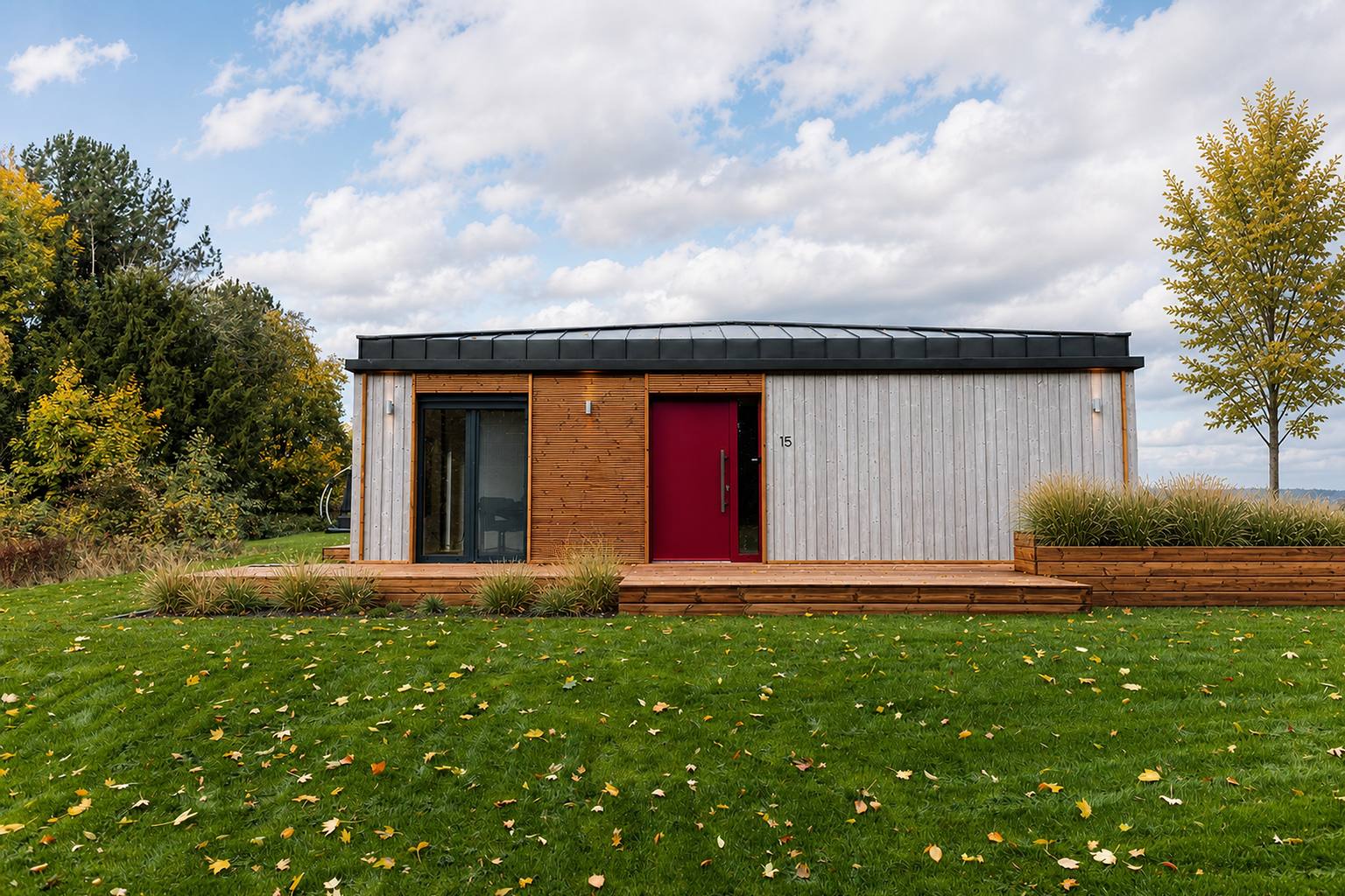 Schlüsselfertiges Dwellii-Modulhaus TR3M, ebenerdig, mit Holzfassade, roter Eingangstür und Rasen im Herbst